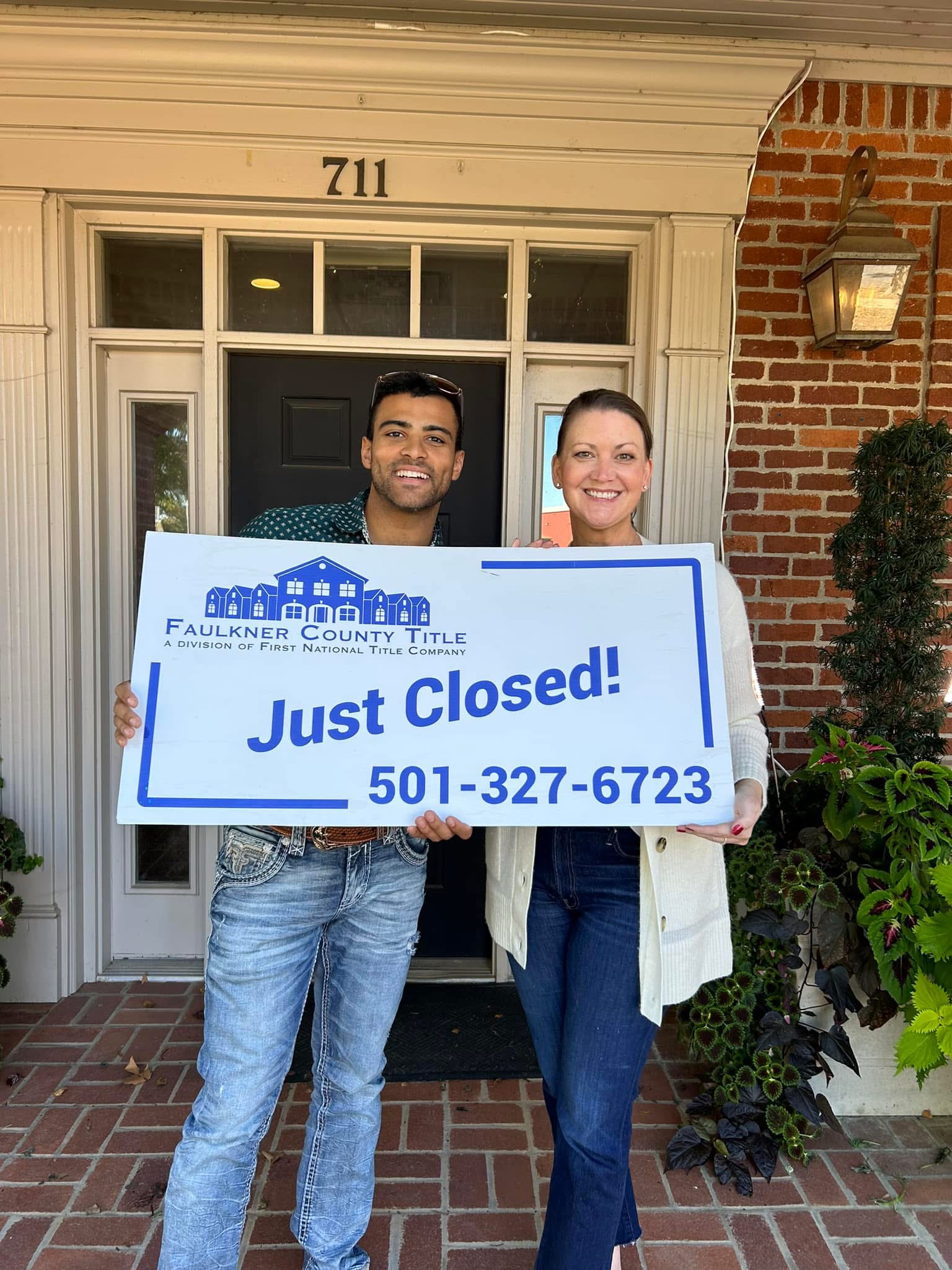 Madison Burke and client holding a just closed sign outside Faulkner County Title